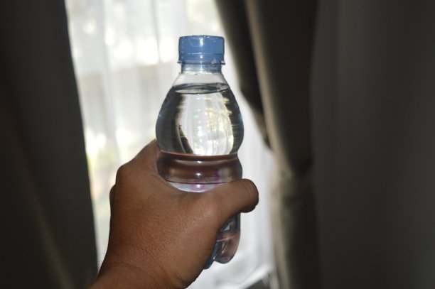 拿着窗帘背景矿泉水塑料瓶的男人。图片下载