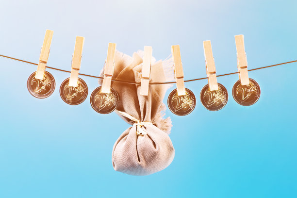 洗钱的概念。蓝色背景的绳子上的硬币，欧元钞票，挂在挂衣服的木制衣夹上。晾干钱清洗或洗黑钱。被夹子夹住的钱。图片下载