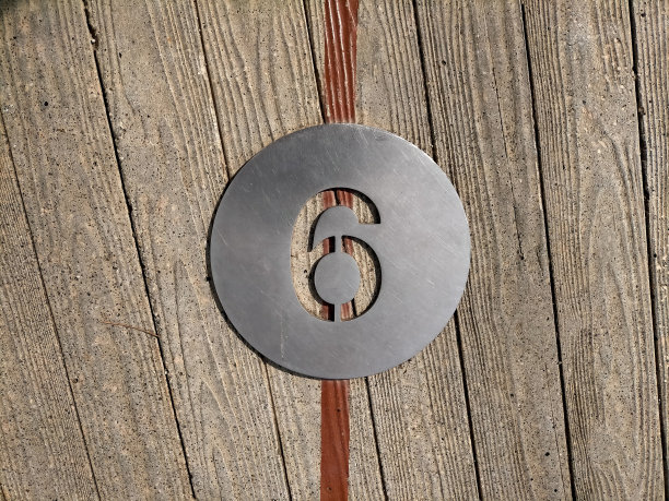 6号，6号在外面木地板上方的圆形金属板上。号码印在车牌上。数字下方垂直画着一条红色的条纹。图片下载