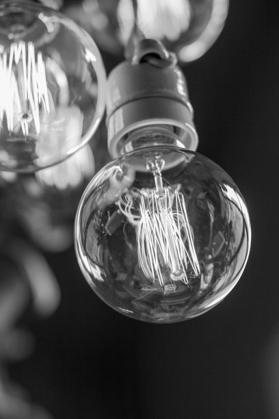 一个点亮的灯泡的单色图像。选择性聚焦在灯丝上。启蒙的概念图片下载