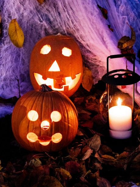 万圣节南瓜展示在蜘蛛网和一个发光的灯笼。图片下载