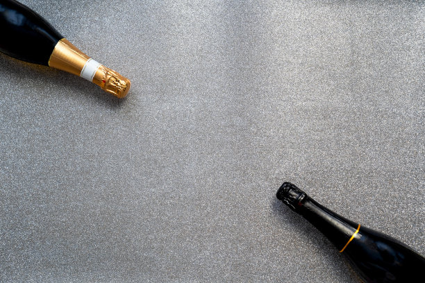 两瓶香槟在银色闪亮的背景，复制空间的文字，节日框架，圣诞快乐和新年快乐的庆祝，婚礼或生日装饰图片下载