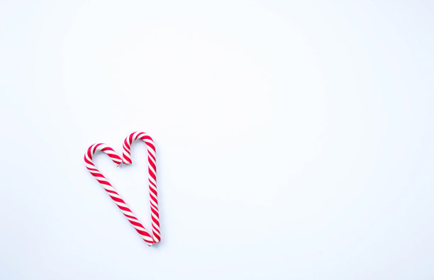 横幅。两个心形条纹糖果棒，白色背景。爱的概念，极简主义，平铺，文字的复制空间。图片下载