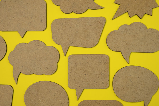 在黄色纸背景上的木制空洞讲话气泡概念与阴影。副本的空间。图片下载