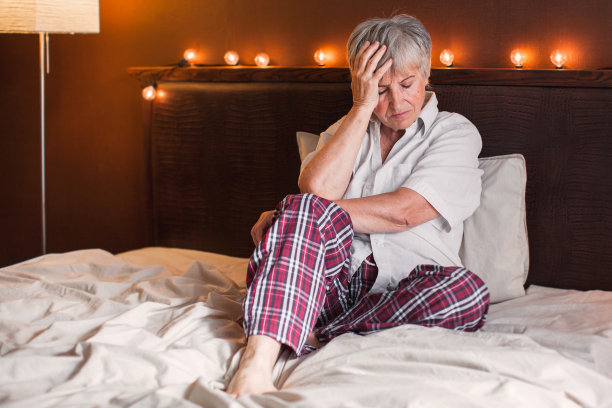 悲伤的不快乐的老年妇女坐在床上的卧室图片下载