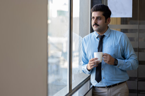快乐的男人一边喝咖啡一边看向别处。图片下载