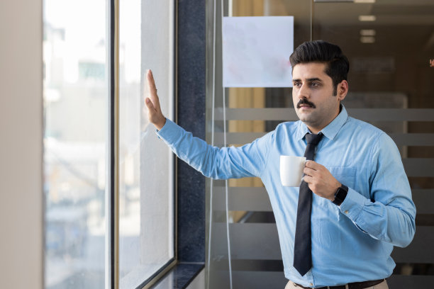 快乐的男人一边喝咖啡一边看向别处。图片下载