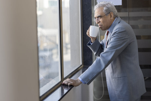在办公室喝咖啡的高级男子看向别处图片下载