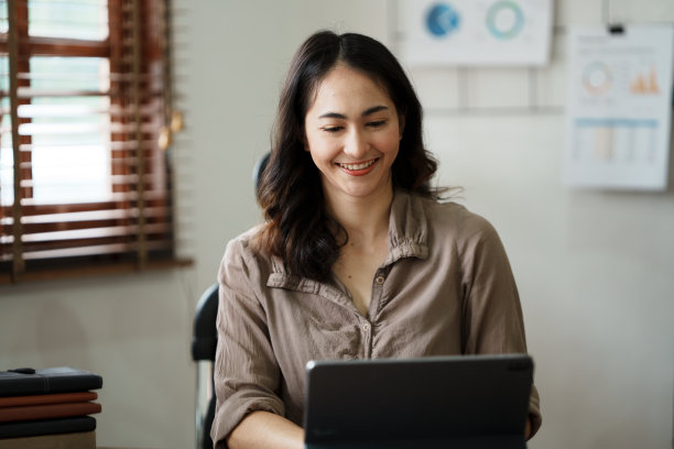 美丽的微笑的年轻女子工作在她的工作场所的电脑在办公室图片下载