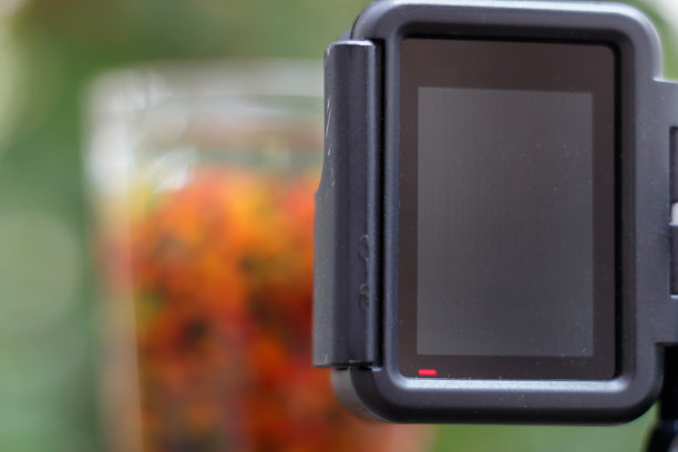 近距离观察一个装满彩色球的玻璃杯。垂直放置在三脚架上的动作摄像机正在记录这一场景。图片下载