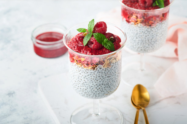 贾布丁。健康的香草奇亚布丁在玻璃与新鲜的覆盆子和薄荷在白色的背景。素食健康的早餐。图片下载