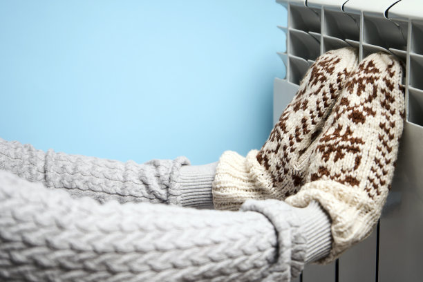 女人在加热器上暖手，特写图片下载