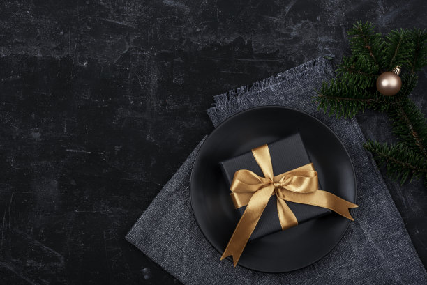 圣诞和新年的黑色餐桌。黑色盘子，礼品盒，杉树和玩具。俯视图，平铺图片下载