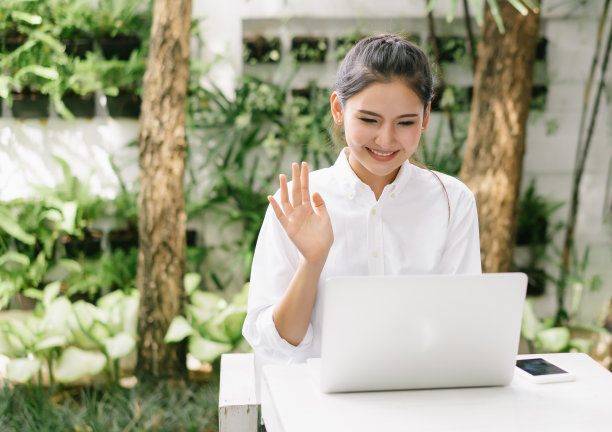 快乐的微笑美丽的亚洲妇女正在家中花园的笔记本电脑上进行视频通话。在网上视频通话、会议、和朋友打招呼时呆在家里。在家工作的概念。图片下载