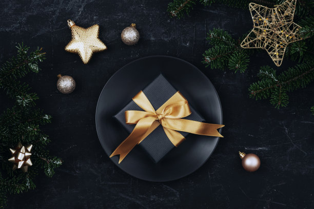 时尚的餐桌设置，礼品盒，明星和球与黑色的背景黑色的盘子。圣诞节的概念。俯视图，平铺图片下载