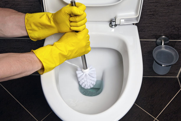 戴着黄色橡胶手套的手用刷子清洁抽水马桶图片下载