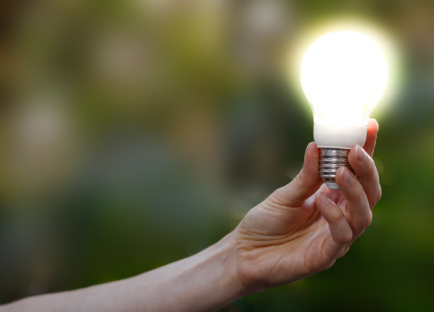 特写一个女人手里拿着一个亮着的灯泡。图片下载