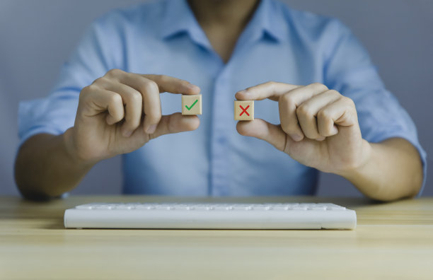 一个商人手里拿着一块木头，上面写着支票、记号和错误。这个想法是决定投票。思考是或否在困难的情况下商业选择真和假符号图片下载