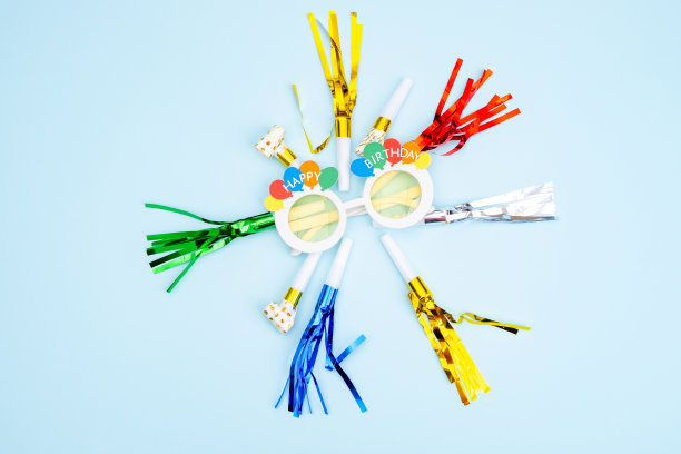 生日晚会的背景。邀请函，派对用品，生日哨子，派对眼镜和帽子，礼品盒，旗帜和餐巾。图片下载