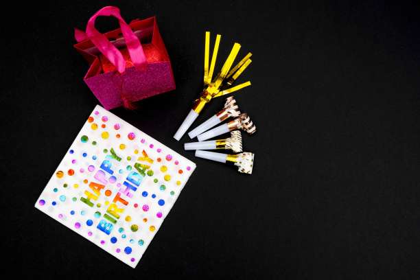 生日晚会的背景。邀请函，派对用品，生日哨子，派对眼镜和帽子，礼品盒，旗帜和餐巾。图片下载