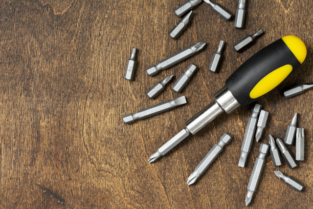 棕色的木桌上放着一把有小块的螺丝刀。俯视图图片下载