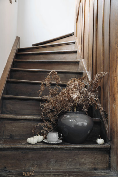 秋天忧郁静物。一杯咖啡，白色南瓜，旧木楼梯上插着干蕨类植物的花瓶。乡村北欧室内。橡木镶框式的大厅。垂直舒适的生活方式照片。有选择性的重点。图片下载