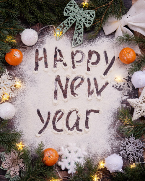 垂直的照片。2023是手写在面粉上的木桌，旁边是云杉树枝、橘子和圣诞玩具。新年的概念。图片下载