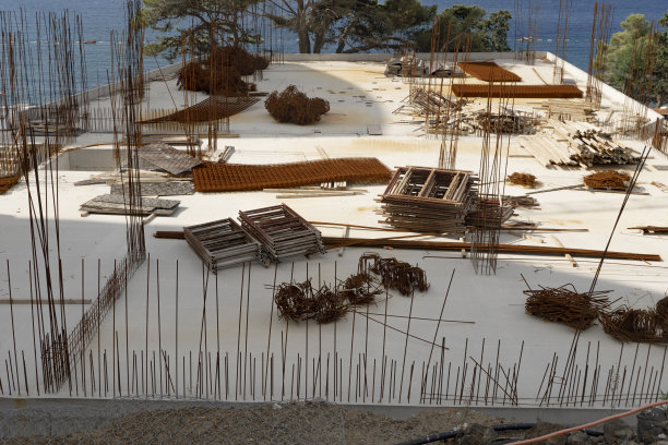 在一座未完工的建筑屋顶上，散落着一大堆因受潮而锈迹斑斑的建筑配件。建筑垃圾污染环境。图片下载