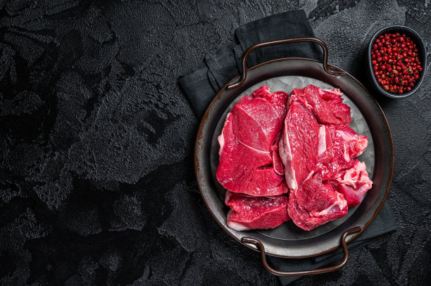肉铺桌上的生羊腿牛排。黑色背景。前视图。本空间图片下载