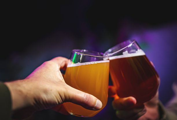 两个朋友在酒吧里手拿精酿啤酒敬酒。酒吧图片下载