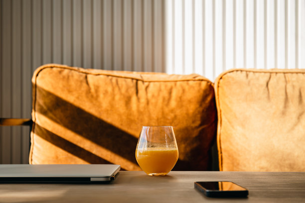 早上在笔记本电脑旁边的桌子上喝一杯橙汁。图片下载