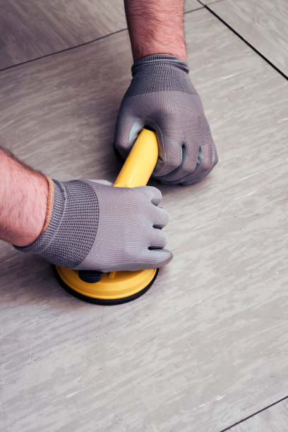 工人手拿真空吸盘吊装地板。一个男人举起地板，特写。图片下载