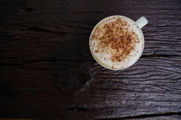 热卡布奇诺在白色杯子木制背景，咖啡是一种受欢迎的饮品在世界各地。图片下载