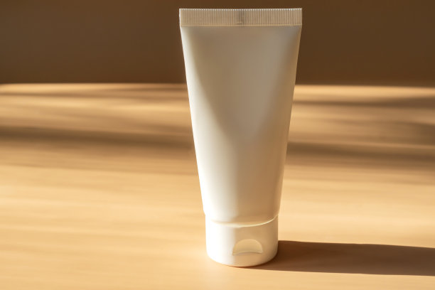 米色背景的SPA化妆品，女性身体和护肤品。天然身体或面部霜在白色塑料管图片下载