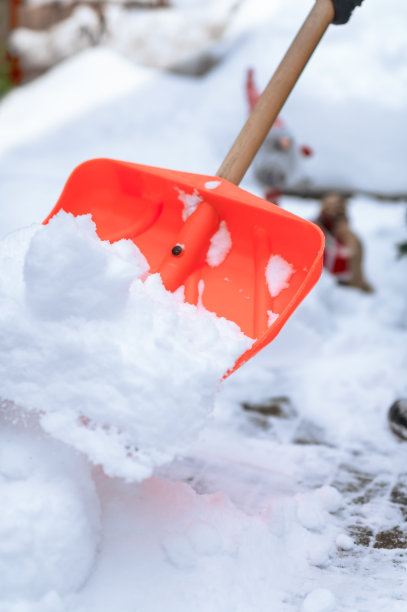 雪上鲜艳的红色铲雪在下雪的户外背景在寒冷的一天图片下载