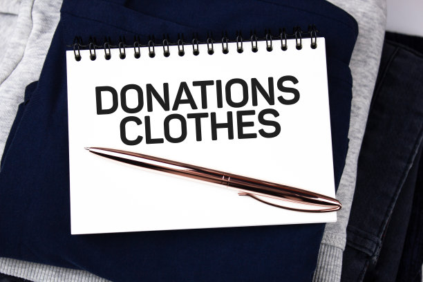 捐赠衣服——放在一堆衣服上的笔记本上的文字。图片下载