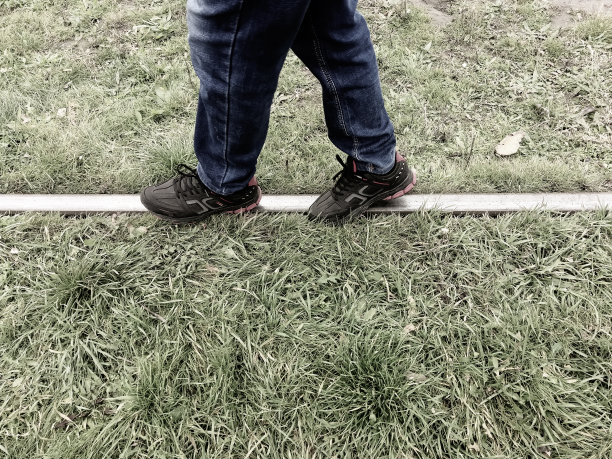 人走在轨道上。铁路上的危险情况。一个穿着运动鞋的人走在铁路上。铁轨上的人。图片下载