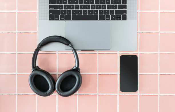 笔记本电脑，耳机和手机在粉色瓷砖或网格背景上，从上面看图片下载
