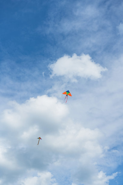 两只彩色的风筝在天空中飘着白色的蓬松的云图片下载