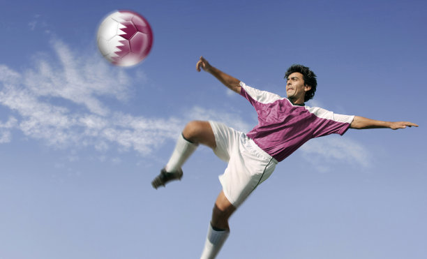 将卡塔尔国旗插在球上的足球运动员图片下载