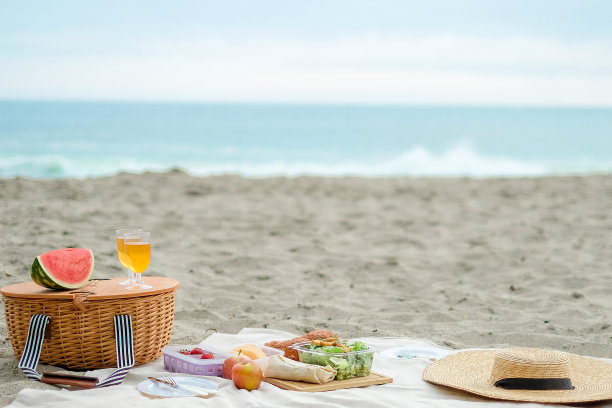 野餐是在海滩上举行的。柳条篮子与食物和饮料的浪漫野餐和放松。冷静和良好的氛围。图片下载
