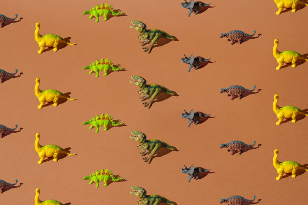 棕色背景上的彩色塑料恐龙玩具。模式。图片下载