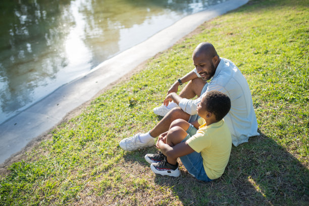 俯视快乐的非裔美国人和男孩坐在水边图片下载