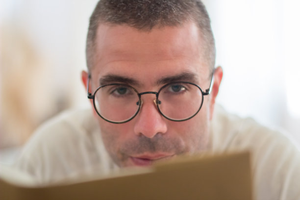 戴眼镜的男人专注地拿着书，看着相机图片下载