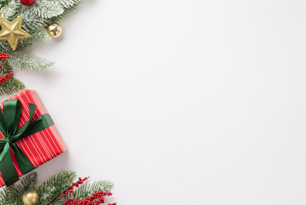 新年的概念。顶视图照片松枝在雪装饰小饰物星星点缀槲寄生浆果和红色礼盒与绿色丝带蝴蝶结孤立的白色背景与空白图片下载