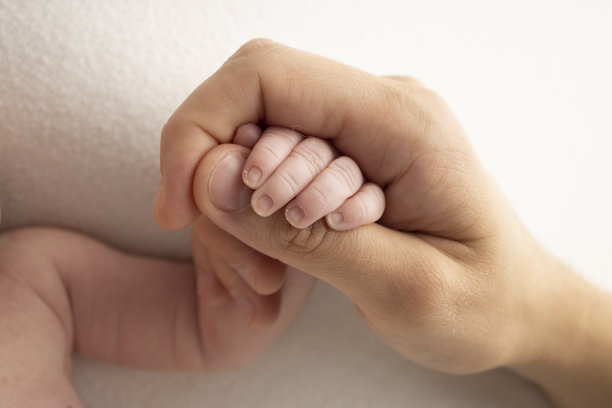 熟睡的新生儿握着父母的手，父母特写。新生儿的小手指。一家人手牵着手。微距摄影工作室。家庭和爱的概念。图片下载