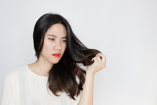 亚洲美女抱着，看着她的发梢，一脸担心地看着分叉干燥的头发图片下载