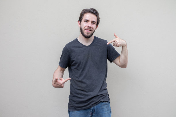 年轻人在深灰色的t恤模型孤立，假打印衬衫，前视图指向他的胸部图片下载