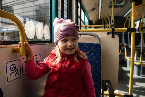 肖像小女孩乘坐公共现代交通公共汽车向窗外望去。可爱的孩子在都市交通，坐在座位上，开心极了。公共交通和城市生活方式的概念。本空间图片下载