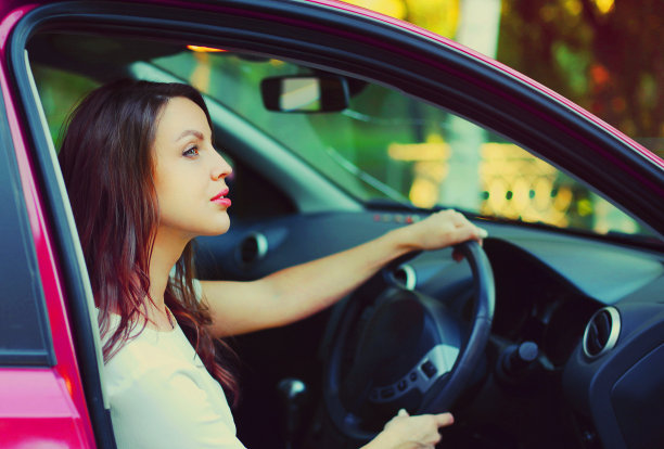 画像美丽的年轻女子司机后面的车轮汽车图片下载